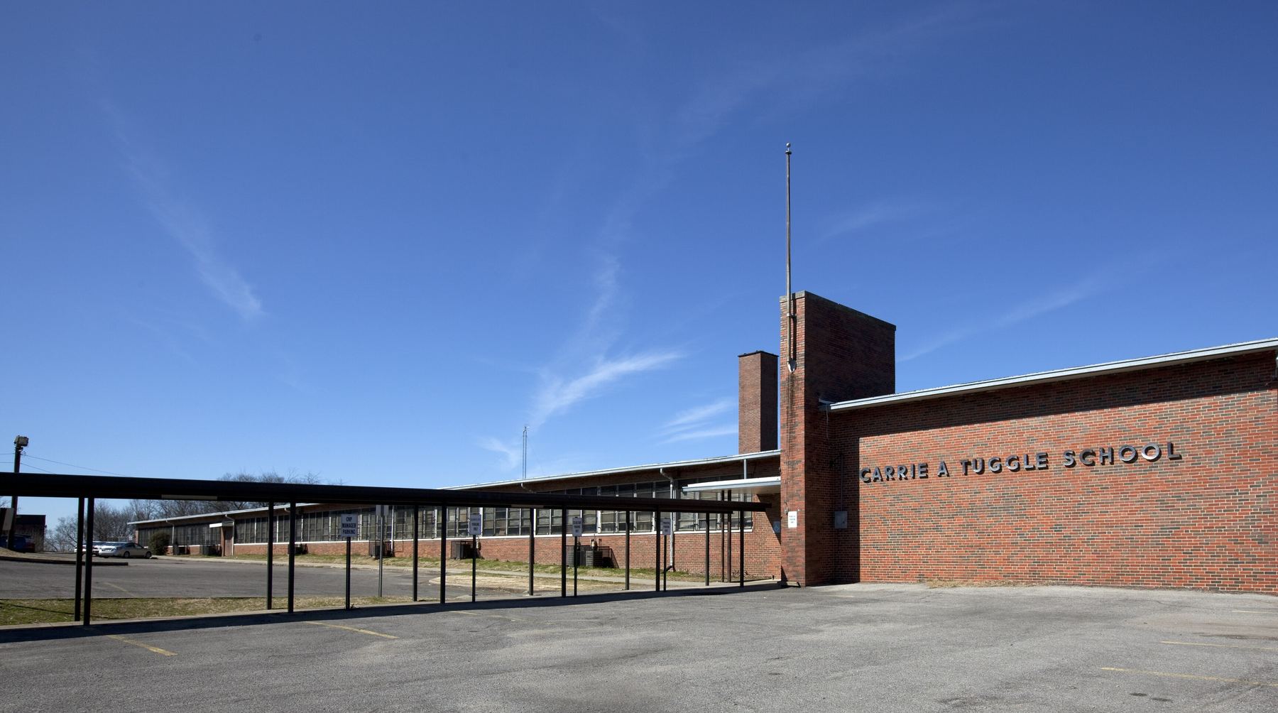 The brick front of Carrie A. Tuggle School on 12th Court North, under a clear blue sky.